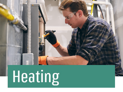 HVAC technician in blue shirt repairing furnace.