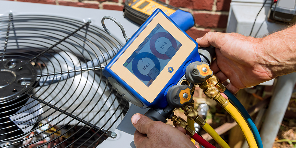 HVAC tech uses tool to perform AC service on outdoor unit.