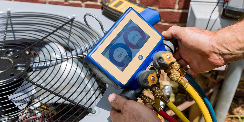 HVAC tech uses tool to perform AC service on outdoor unit.